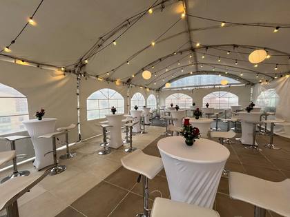 Carpa lounge con mesas de coctel y luces